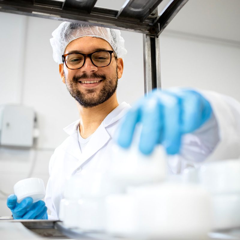 Close up view of pharmaceutical worker technologist working in cosmetics factory with healthcare creme products.